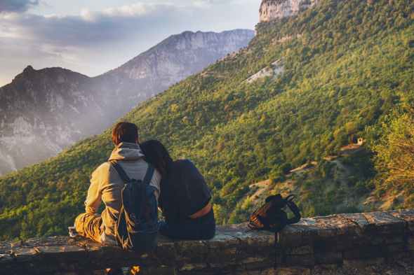couples sitting in while facing mountain